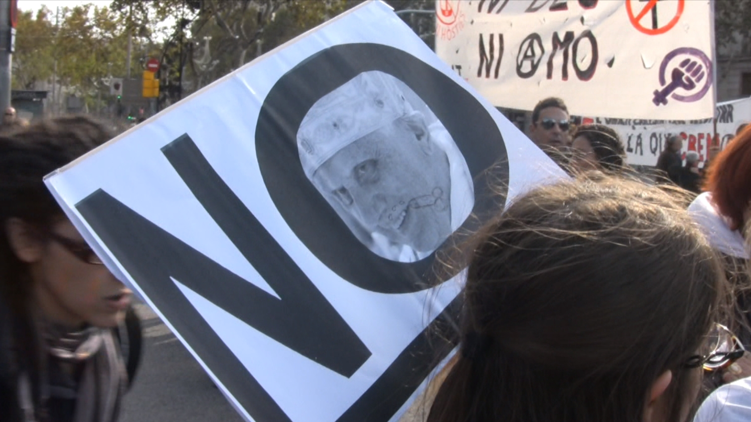 En resposta a la visita del Papa i la rebuda de la Mama.
<br/>
<br/>La Barcelona anticlerical rep la Mama i rebutja el Papa.
<br/>
<br/>L'acte de rebuig a la visita papal convocat per la campanya 'Deixem-nos d'hòsties! Jo no t'espero!' va comptar amb unes 500 persones que es van concentrar el diumenge 7 a les 12 del migdia a la confluència del Passeig de Gràcia amb la Gran Via. Moltes de les persones venien de la concentració que s'havia fet a la plaça Universitat convocada per Ca la Dona sota el lema 'Les dones no t'esperem!'.
<br/>
<br/> La pancarta principal deia 'Deixem-nos d'hòsties. Som el pecat i ens agrada' i es podien veure altres pancartes i plafons amb lemes com 'L'església que il·lumina és la crema', 'Mort al PApaTRIARCAT', 'Avortament lliure i gratuït!' entre d'altres.
<br/>
<br/>Marc Garriga, portaveu de la campanya va presentar l'acte des d'un escenari acompanyat de la banderola amb el lema de la campanya que aquests dies s'han anat repartint arreu. Garriga llegí el manifest que començava amb la dada que ' l'estat continua avui finançant la confessió catòlica amb uns 6000 milions d'euros anuals, dels quals la meitat es destina a mantenir col·legis religiosos concertats' i destacava que 'l'episcopat catòlic no ha deixat de pronunciar-se críticament contra el reconeixement de drets fonamentals (...)oposant-se al dret de morir dignament i al dret de les dones a decidir sobre el propi cos a l'hora de portar a terme o no un embaràs. Tractant d'imposar la seva visió de la sexualitat, purament reproductiva, condemna altres formes de viure-la. Desaprova l'ús dels mètodes anticonceptius i de manera greument irresponsable crida a incomplir les recomanacions internacionals que advoquen per l'ús del preservatiu com a eina provadament eficaç per prevenir la SIDA. Alhora, sense massa escàndol ni vergonya, els nombrosos delictes protagonitzats per capellans catòlics fets públics en els darrers anys romanen sense cap mena de condemna ferma per part de les jerarquies eclesials'.També el manifest denuncia que 'l'església catòlica estigmatitza i criminalitza a les persones gais, lesbianes, transsexuals i bisexuals' i acaba dient que 'és indignant que en un període de crisi i de retallades socials els poders públics contribueixin a finançar les enormes despeses que comporta aquesta visita amb els nostres impostos, siguem o no creients'.
<br/>Seguidament, va pujar a l'escenari l'activista trans Manuela Trasobares amb el puny alçat, la 'Mama' que s'anunciava en la convocatòria ('Vine a rebre la Mama!') i que les manifestants van aclamar amb crits de 'Mama! Mama! a tu sí que t'esperem!'.
<br/>La Manuela Trasobares va recordar que no només hem de rebutjar la visita del Papa i lluitar per una ciutat laica, sinó que cal destruir l'església i l'estat opressor, capitalista i patriarcal.L'activista també va fer un homenatge a les lluitadores llibertàries del 36 que van omplir els carrers de lluita anticlerical i va fer una crida per recuperar aquella il·lusió i revolta i aturar així l'ofensiva catòlica que patim. Manuela va concloure dient que 'aquest sistema podrit només el podrem canviar amb la Revolució'.
<br/>
<br/>L'acte, que va comptar amb el suport i participació activa de l'anarquisme, l'esquerra independentista i col·lectius contra l'homofòbia i la transfòbia,es va concloure amb l'actuació anticlerical de la cantautora electrònica Plutón i la passejada amb 'Mama Mòbil' d'una activista que amb un megàfon va animar a les concentrades a cridar lemes com 'Llibertat sexual! Dret al propi cos!' o 'Traieu els rosaris dels nostres ovaris!'.
<br/>
<br/>Quan ja tocaven dos quarts de dues, es va iniciar una manifestació que va seguir per la Gran Via només alguns metres perquè els Mossos havien muntant un dispositiu tallant el carrer i impedint el pas al carrer Pau Claris, per on passava la comitiva del Papa. Pocs minuts després, es va poder veure com passava el Papa Mòbil i es van poder sentir més fort que mai els crits de 'Jo no t'espero!'.
<br/>Una mica més tard, desconvocat ja l'acte de protesta, quan algunes de les persones que havien estat a la concentració estaven a la Rambla van ser assaltats per la Brigada Mòbil dels Mossos que van colpejar-los retenint unes 25 persones durant un mitja hora amb l'avís de multes futures.
<br/>
<br/>Des de la campanya 'Deixem-nos d'hòsties! Jo no t'espero!' denunciem la violència dels Mossos d'Esquadra i ens solidaritzem amb les persones que poden rebre futures multes.<br/>